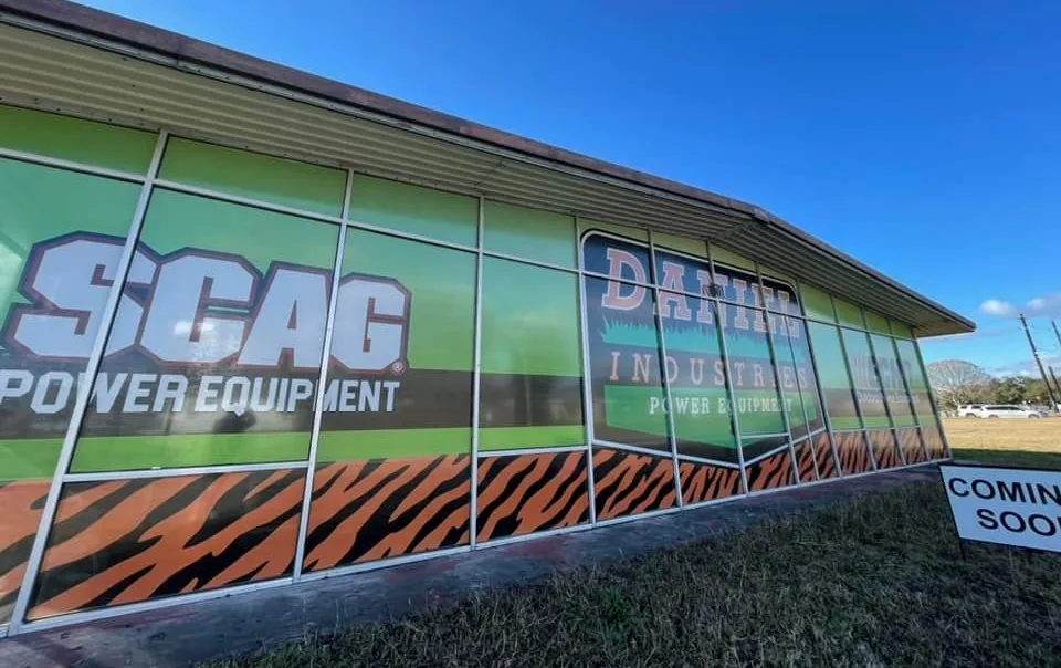 Storefront window graphics beside a post-mounted site sign
